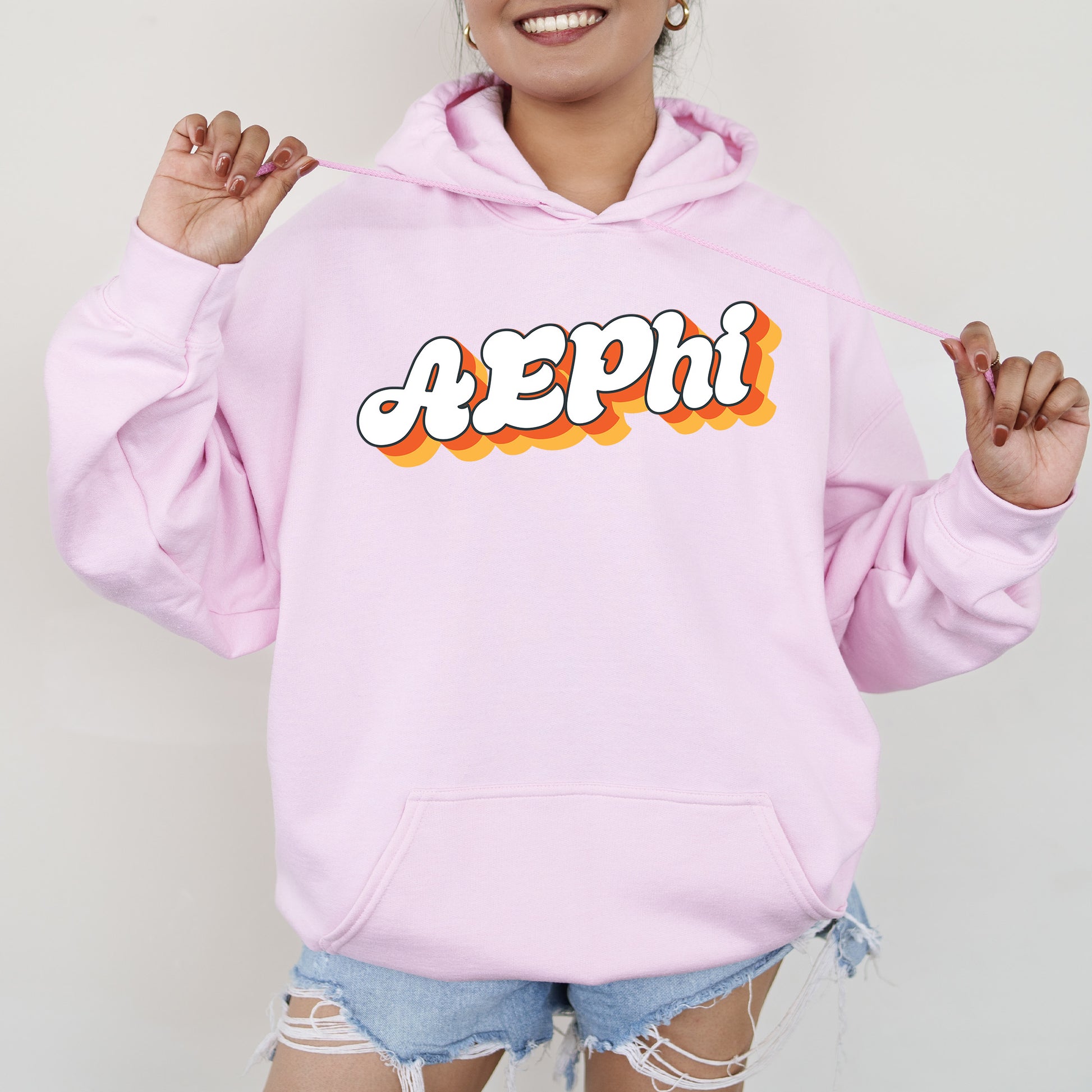 a woman wearing a pink hoodie with the word aeppi printed on it