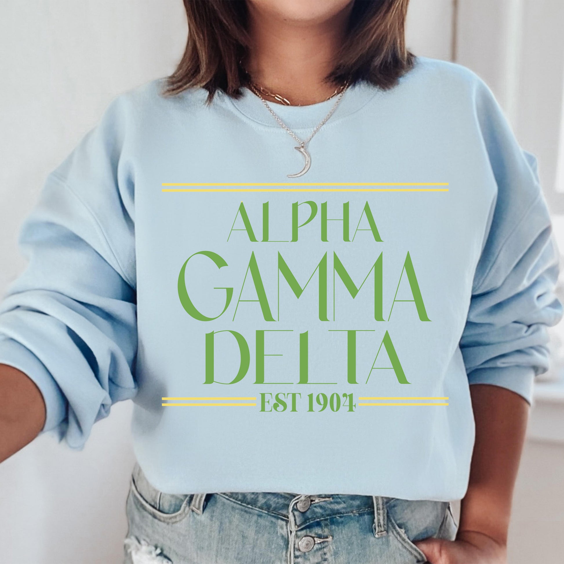 a woman wearing a blue sweatshirt with the words, alpha gama delta est