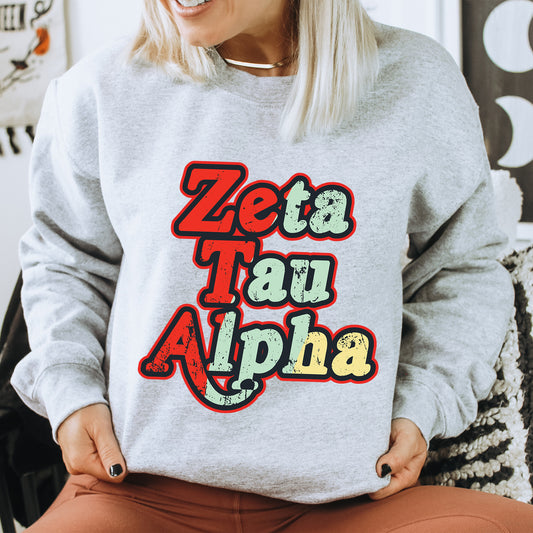 a woman sitting on a chair wearing a sweatshirt with the words zeta tau ah