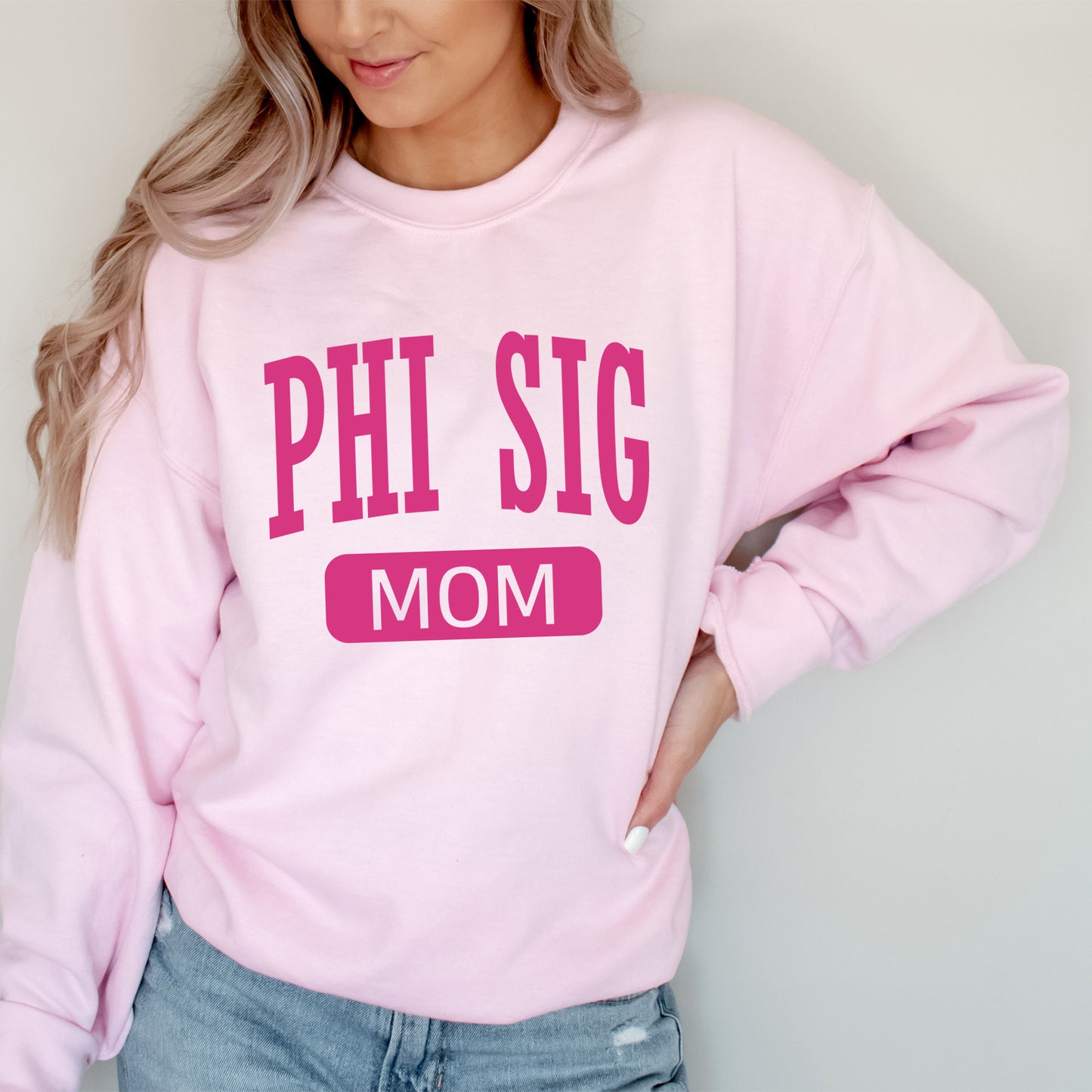 a woman wearing a pink sweatshirt that says phi sig mom