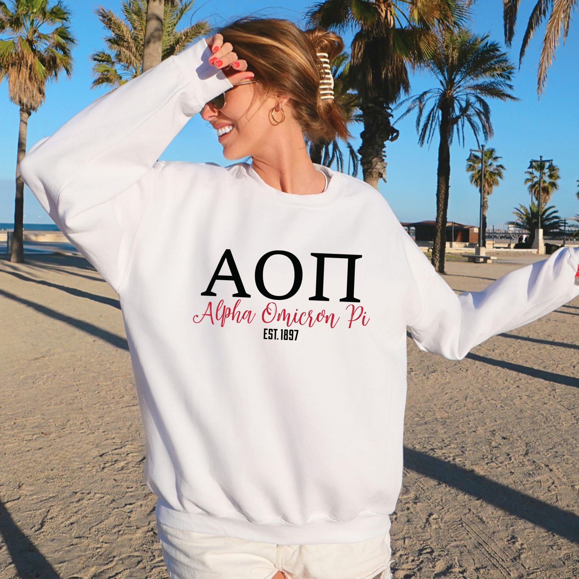 a woman standing on a beach wearing a white sweatshirt