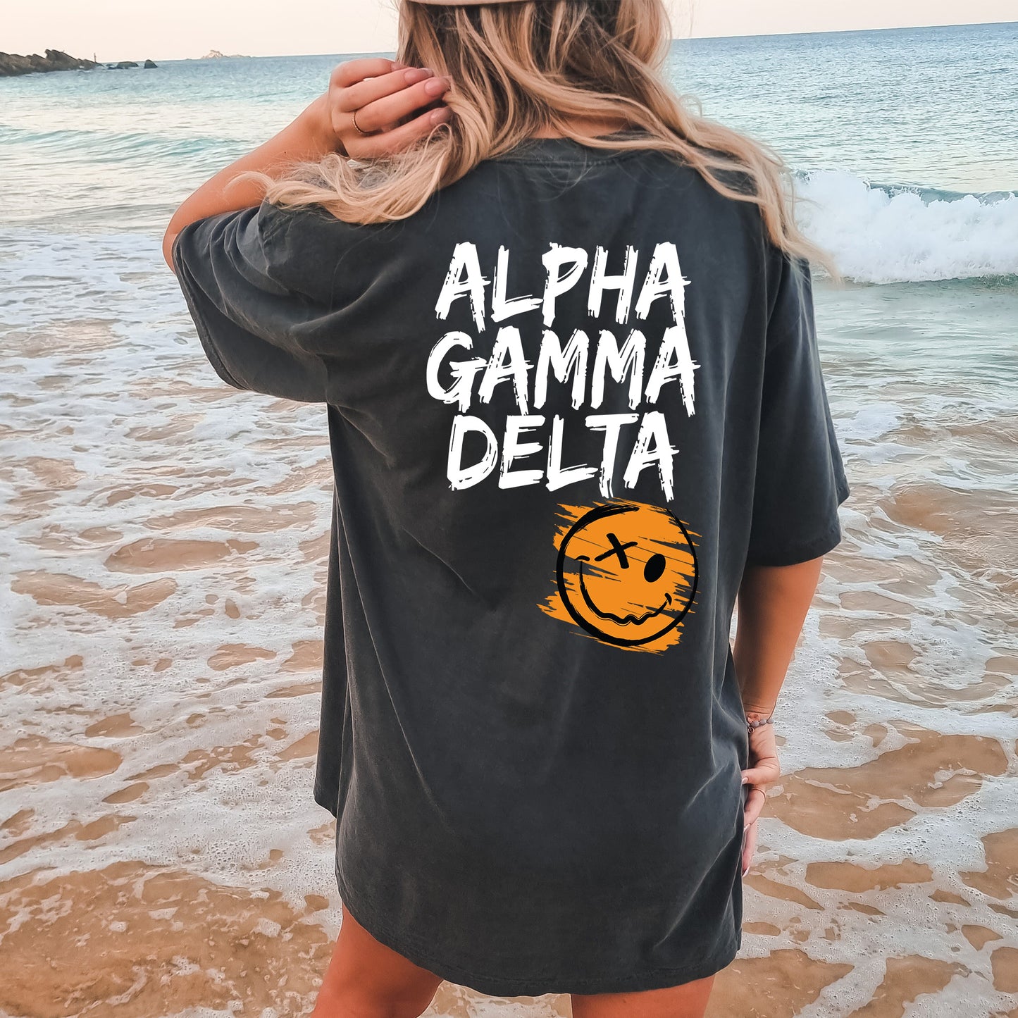 a woman standing on a beach wearing a black shirt