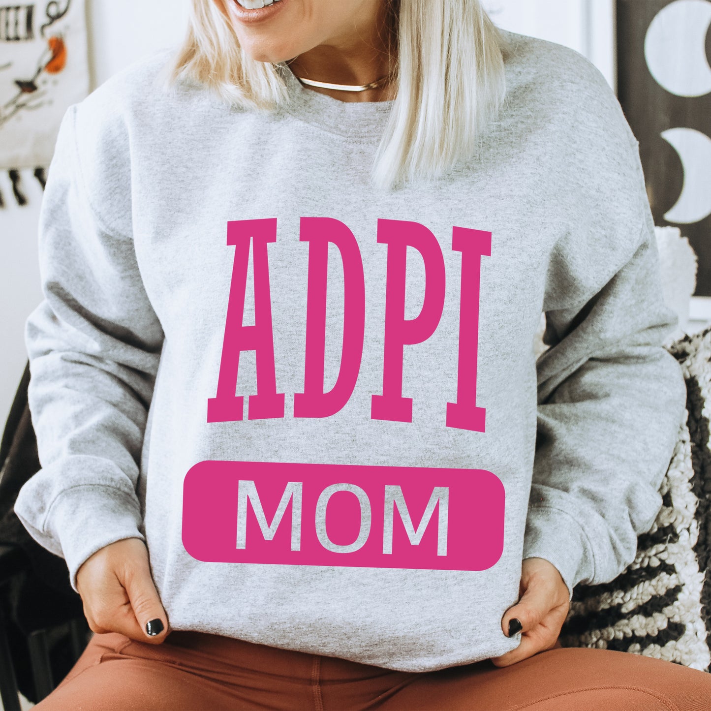 a woman wearing a sweatshirt with the words adpi mom on it