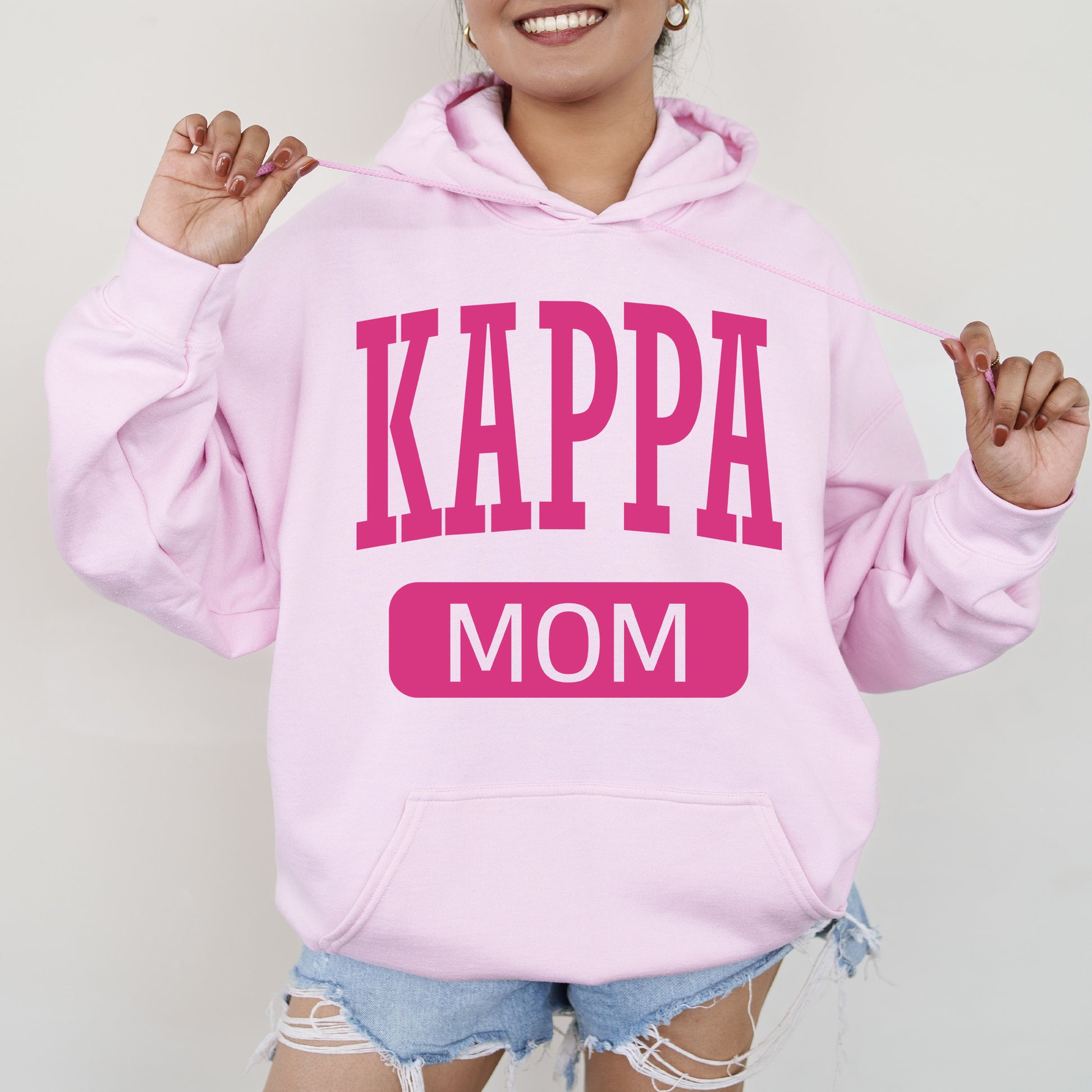 a woman wearing a pink hoodie that says kappa mom