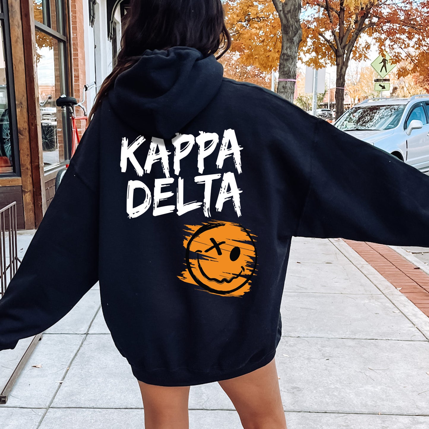 a woman in a black hoodie is walking down the street