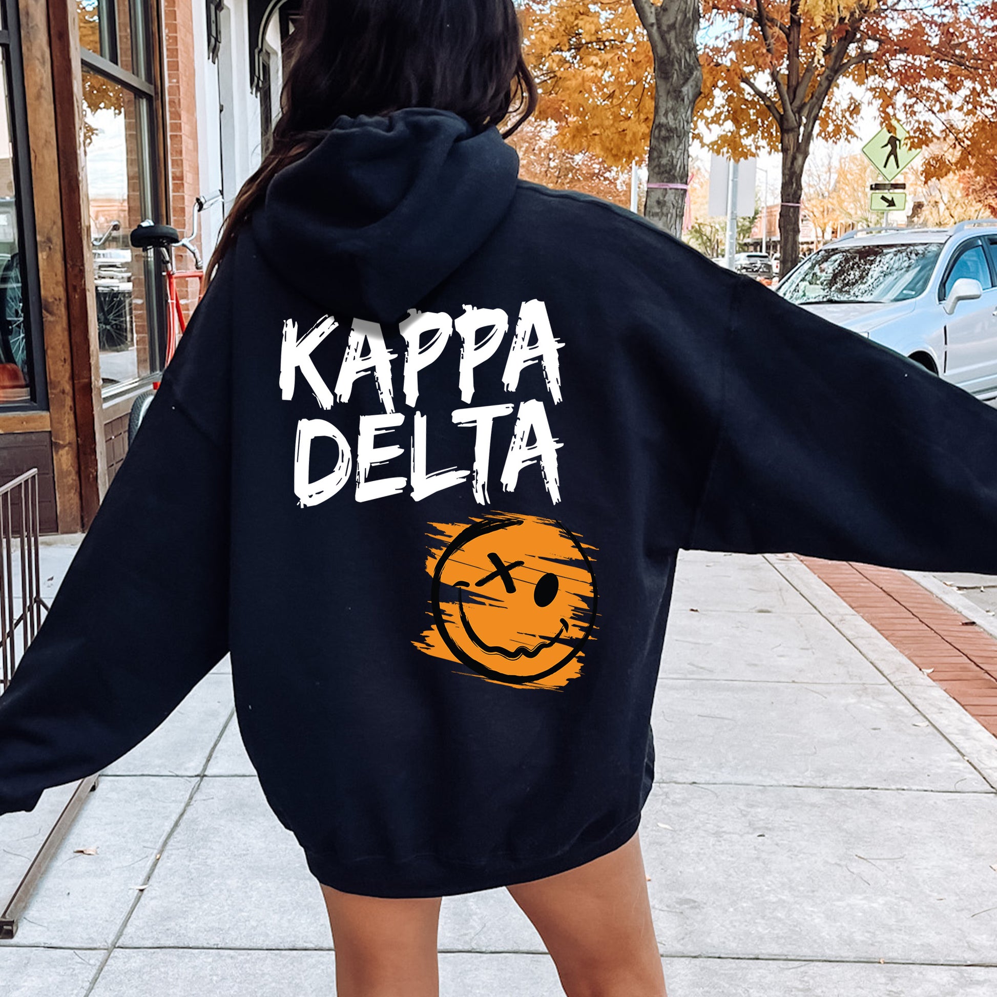 a woman in a black hoodie is walking down the street