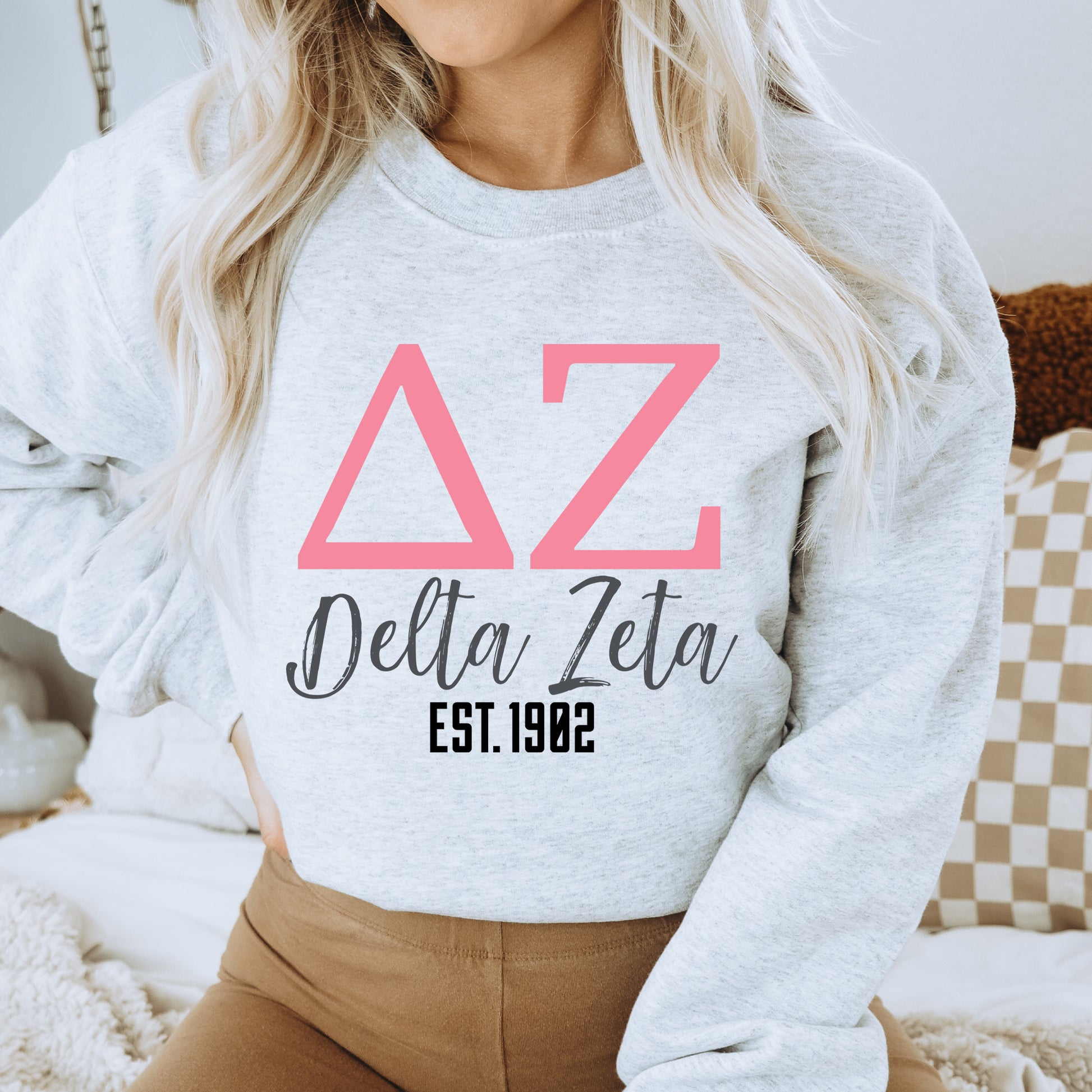 a woman wearing a delta delta sweatshirt and brown pants
