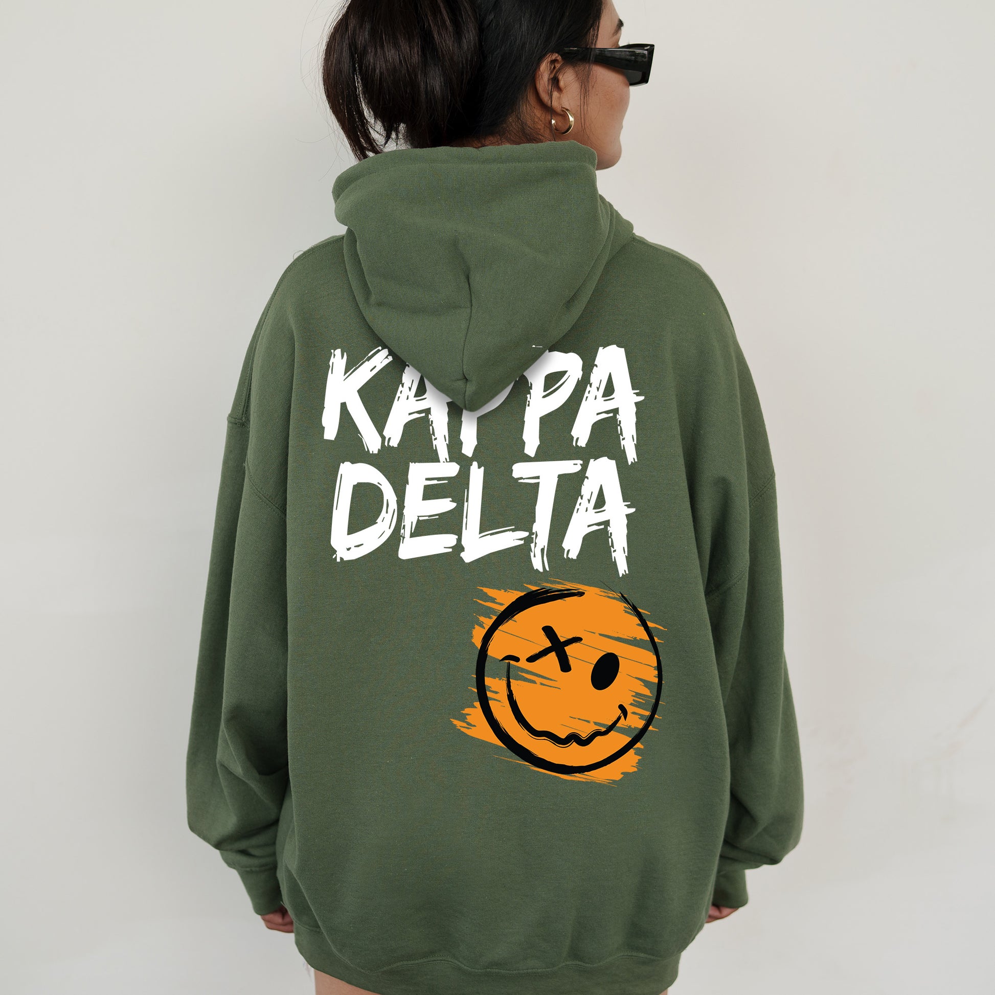 a woman wearing a green sweatshirt with a smiley face on it