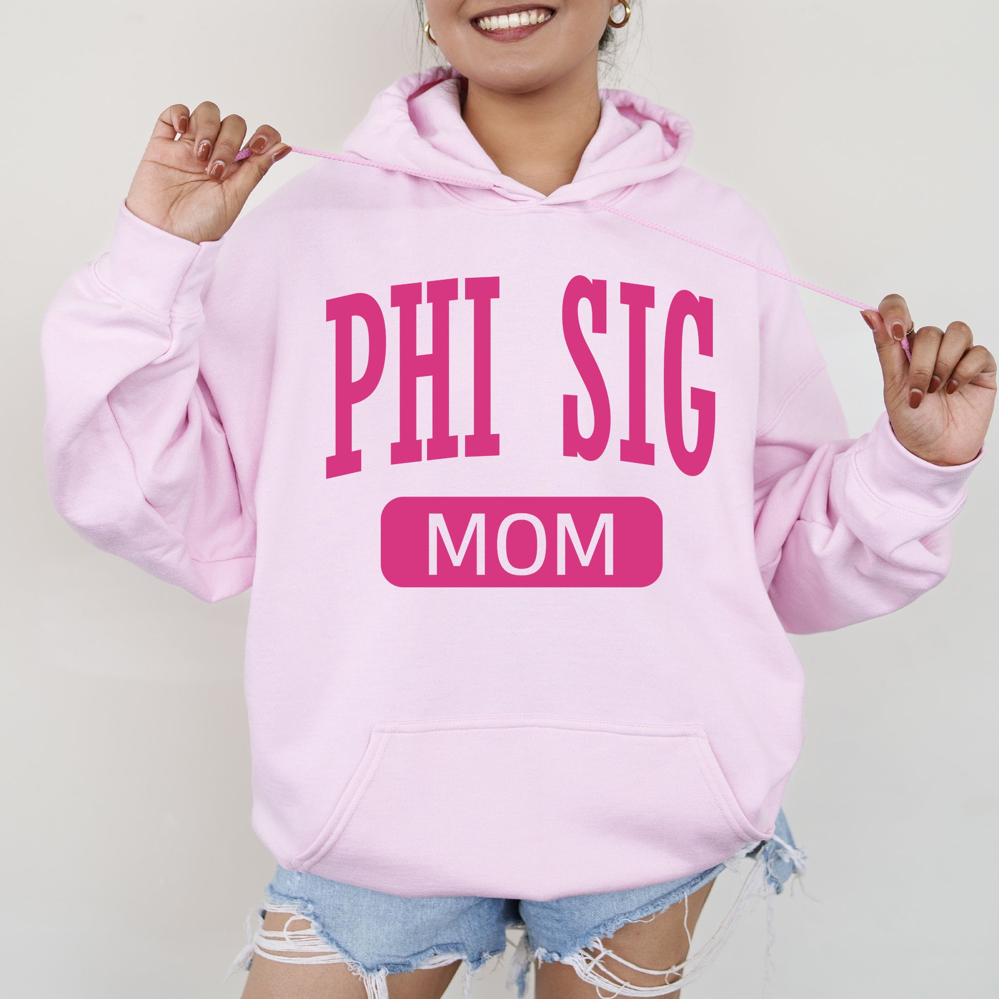 a woman wearing a pink hoodie that says phi sig mom