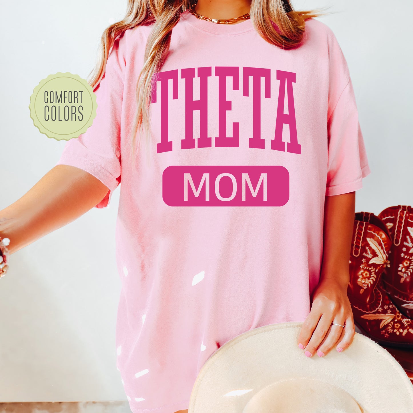 a woman wearing a pink t - shirt with the word theta on it
