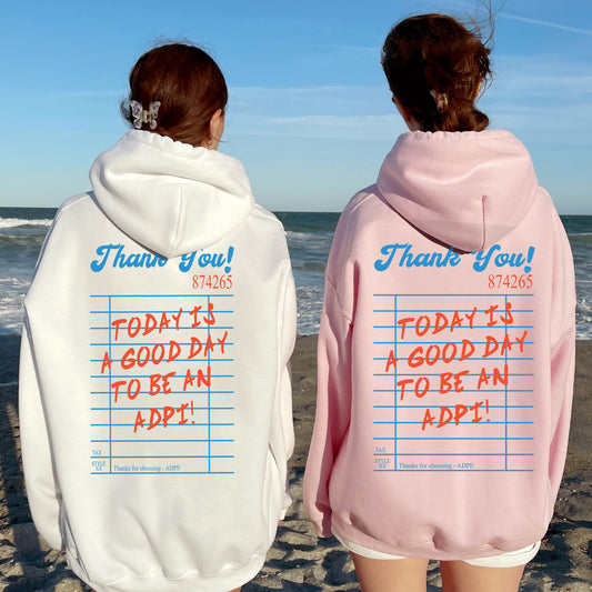two people standing on a beach wearing matching sweatshirts