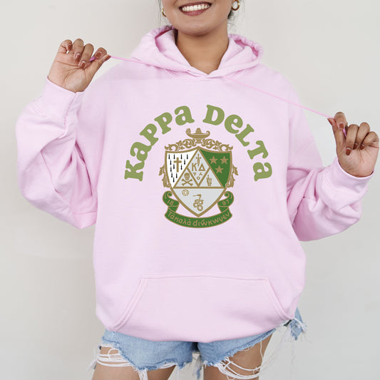 a woman wearing a pink hoodie with a crest on it