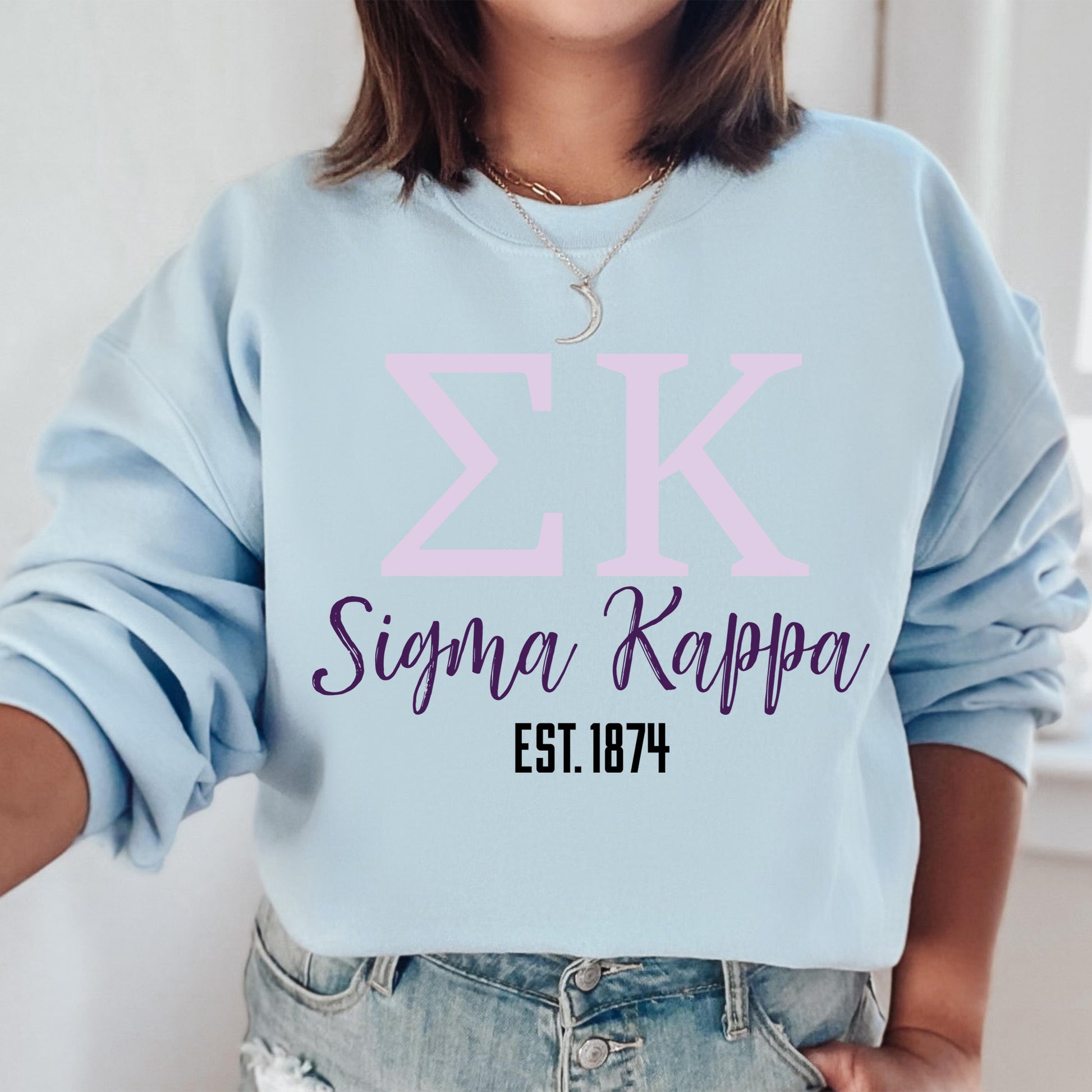 a woman wearing a blue sweatshirt with a pink zk on it