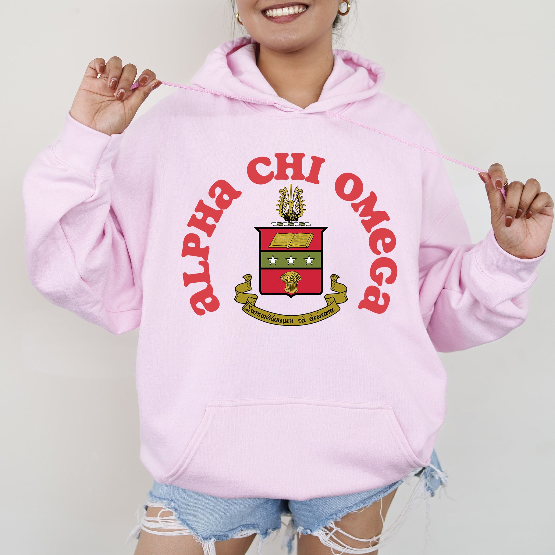 a woman wearing a pink hoodie with a crest on it