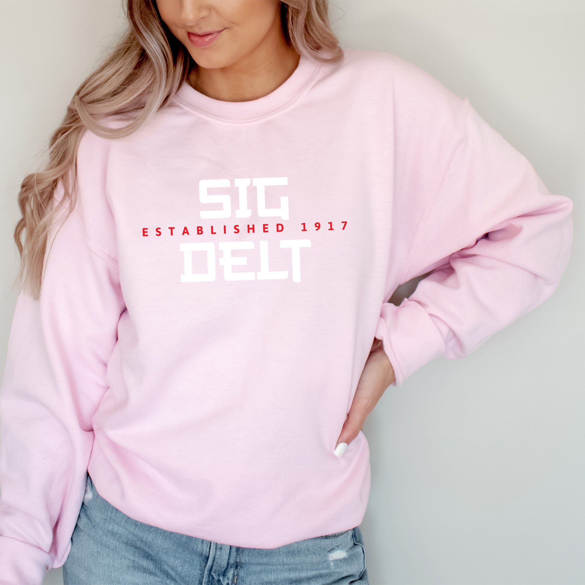 a woman wearing a pink sweatshirt and jeans
