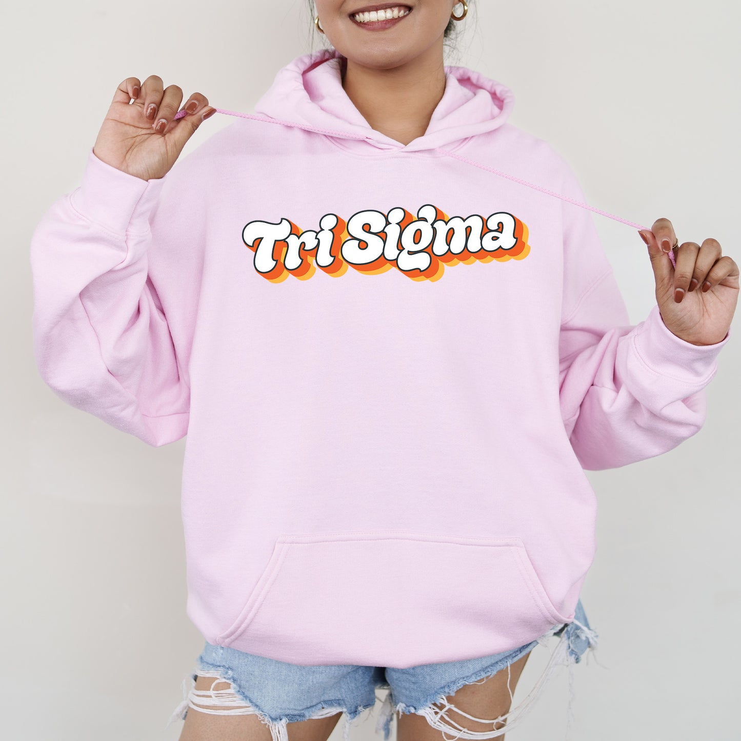 a woman wearing a pink hoodie with the word tri stigma on it