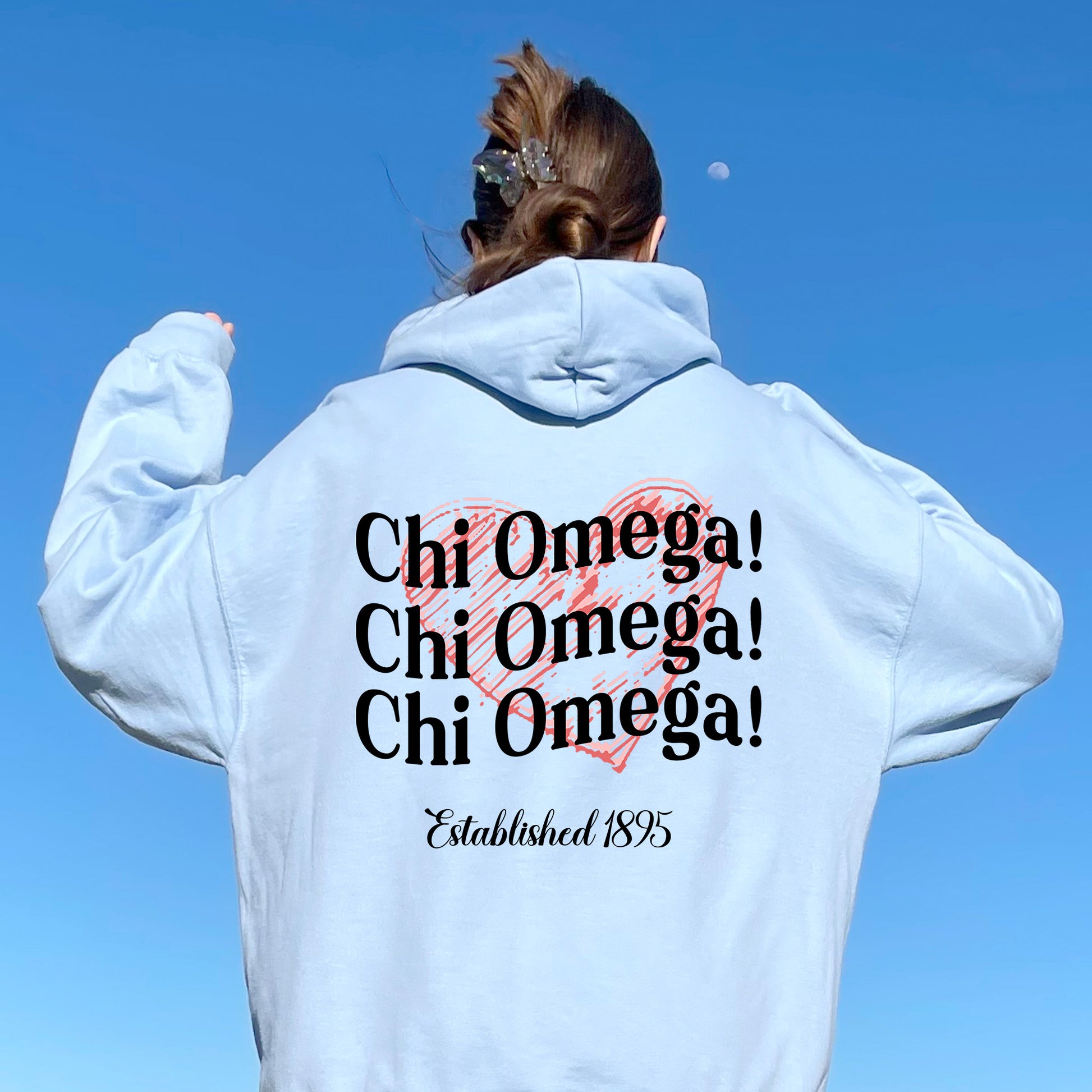a woman wearing a white hoodie with the words chi omega written on it