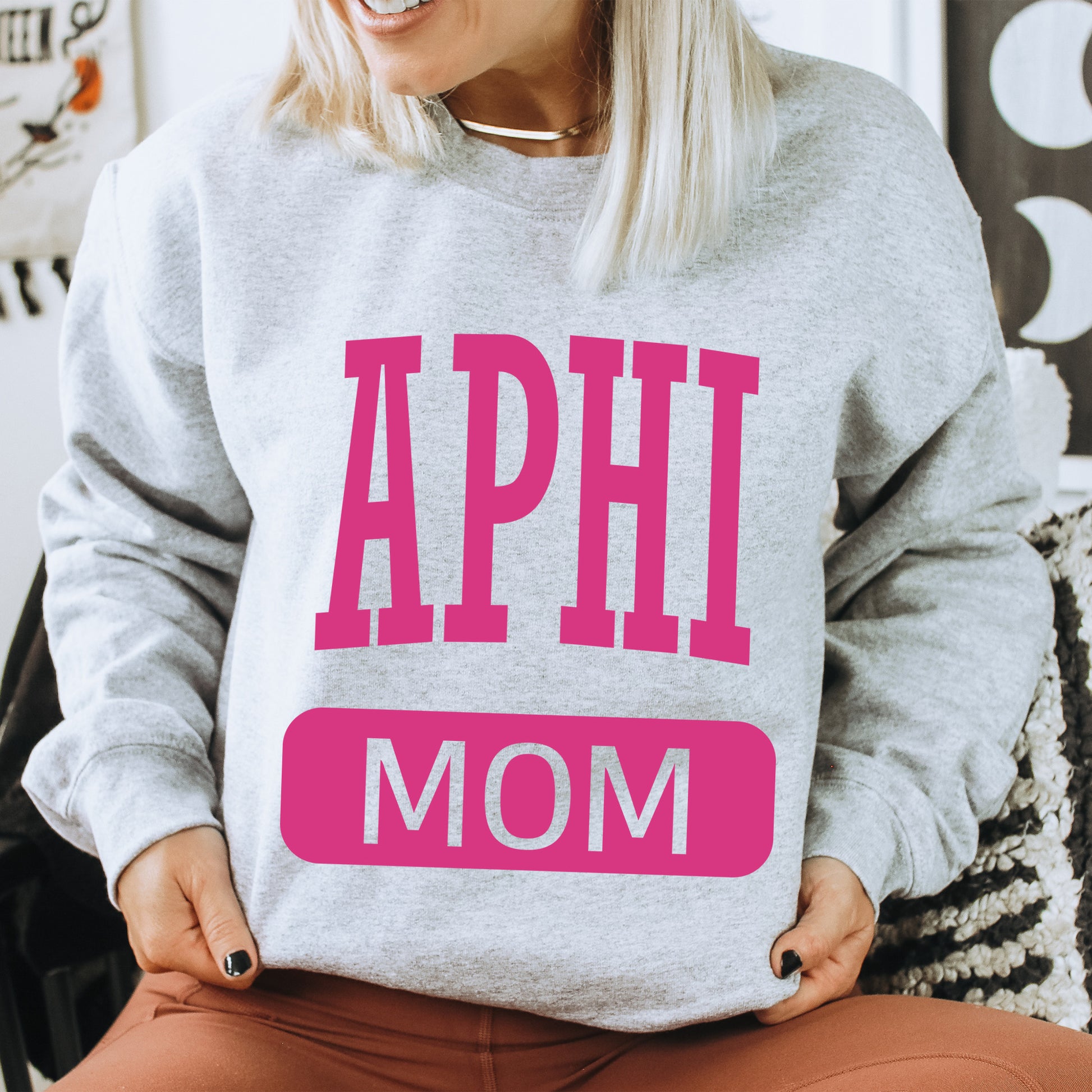 a woman wearing a sweatshirt that says aphi mom
