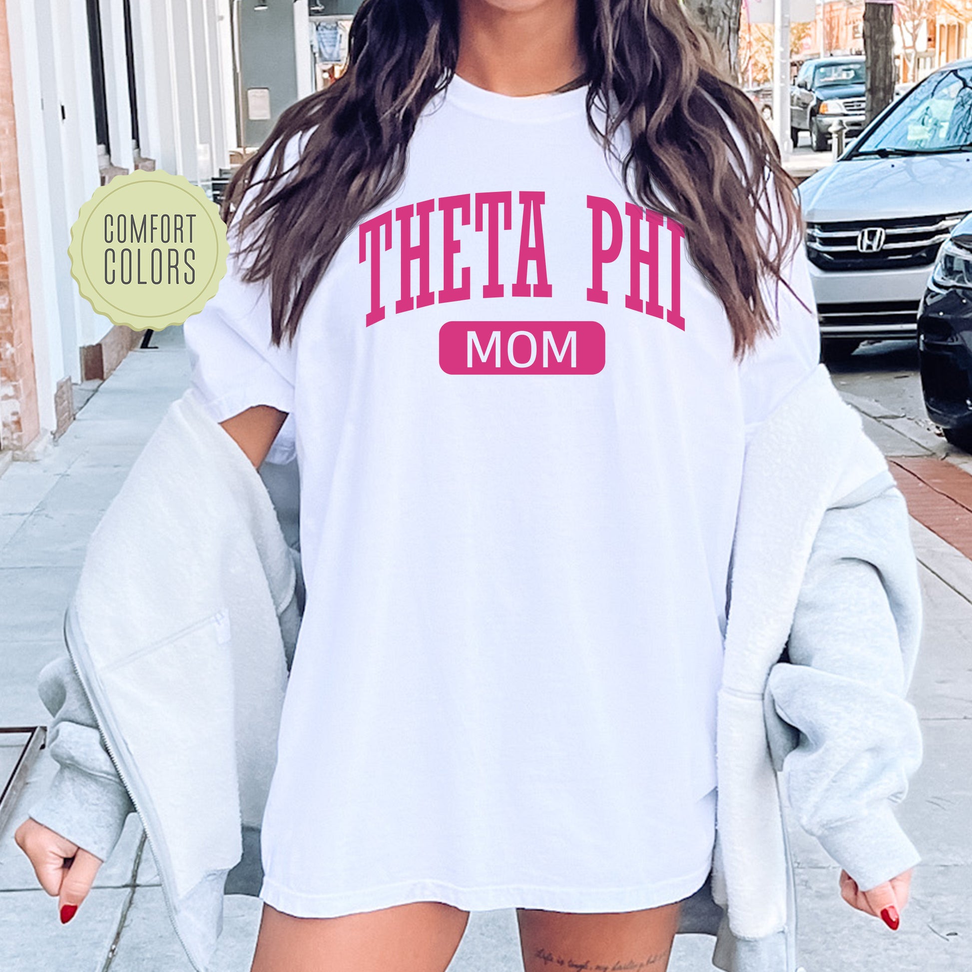 a woman wearing a white shirt that says thea phi mom