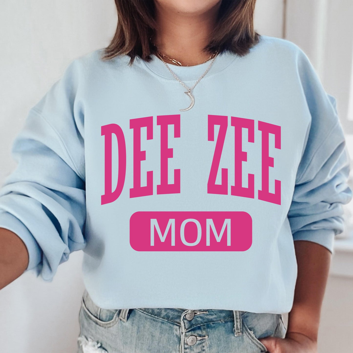 a woman wearing a sweatshirt that says dee zeee mom