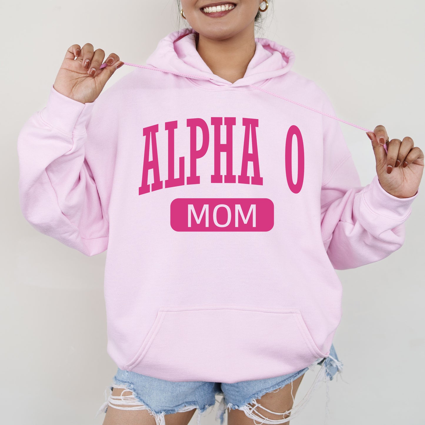 a woman wearing a pink hoodie that says,'alpha o mom '