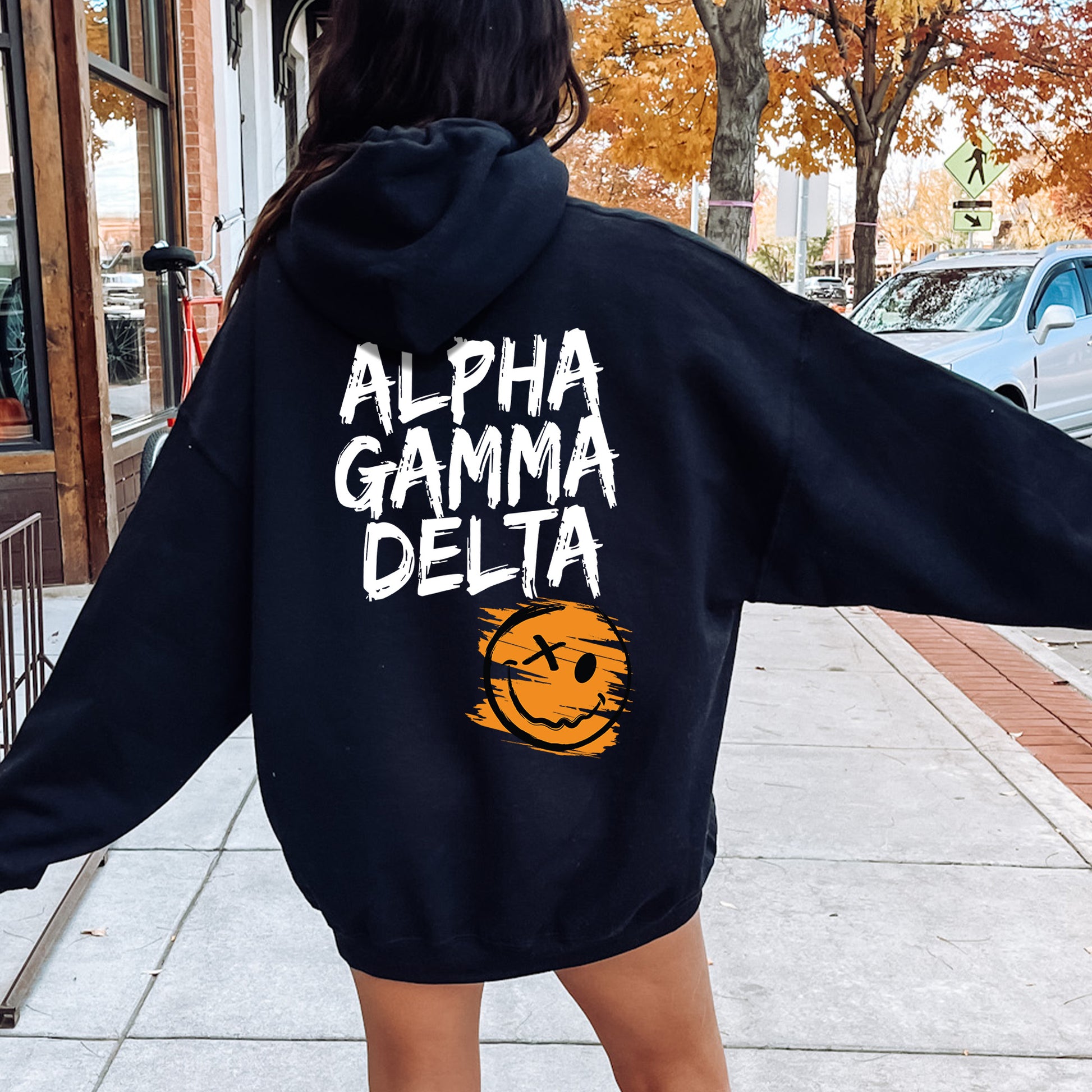 a woman in a black hoodie is walking down the street