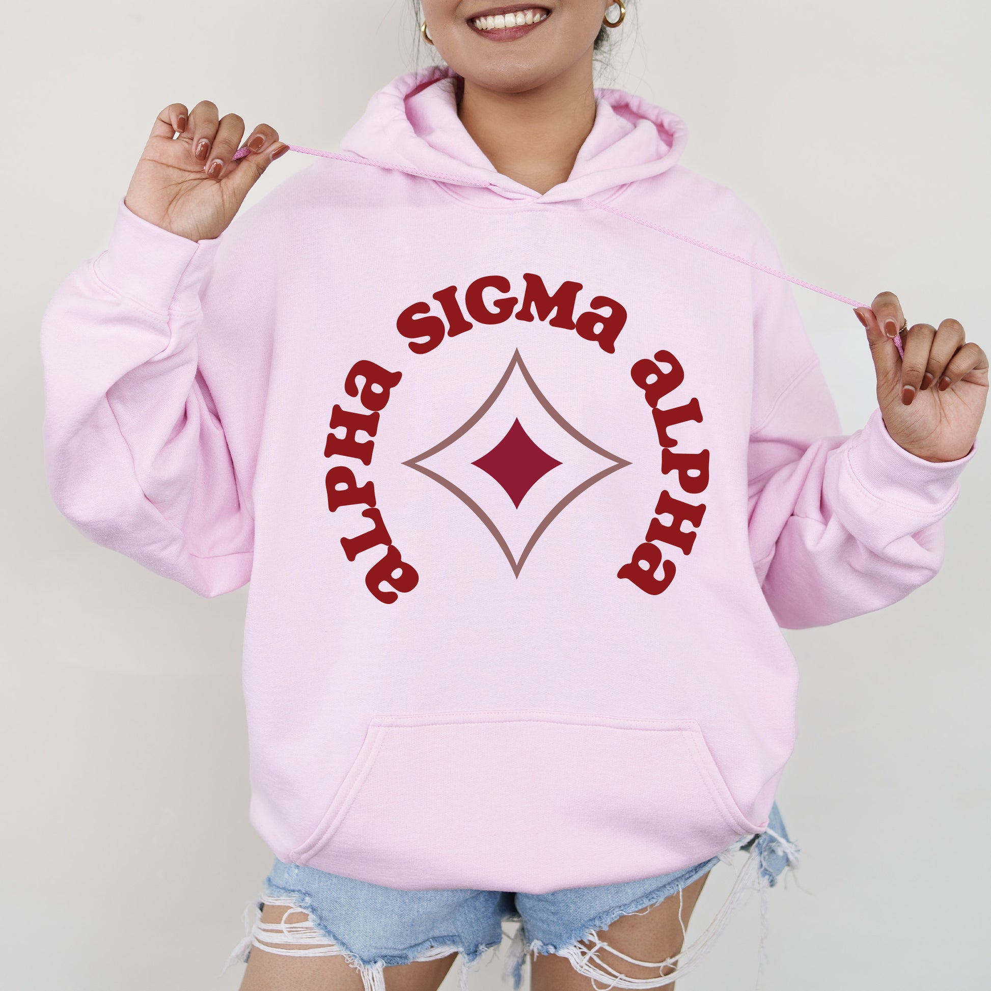 a woman wearing a pink hoodie with a diamond on it