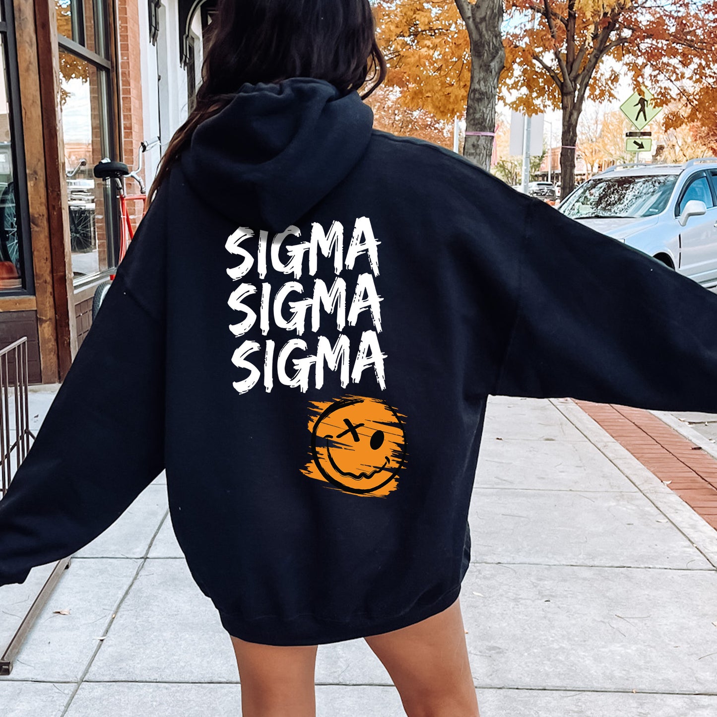 a woman walking down a sidewalk with a black sweatshirt on