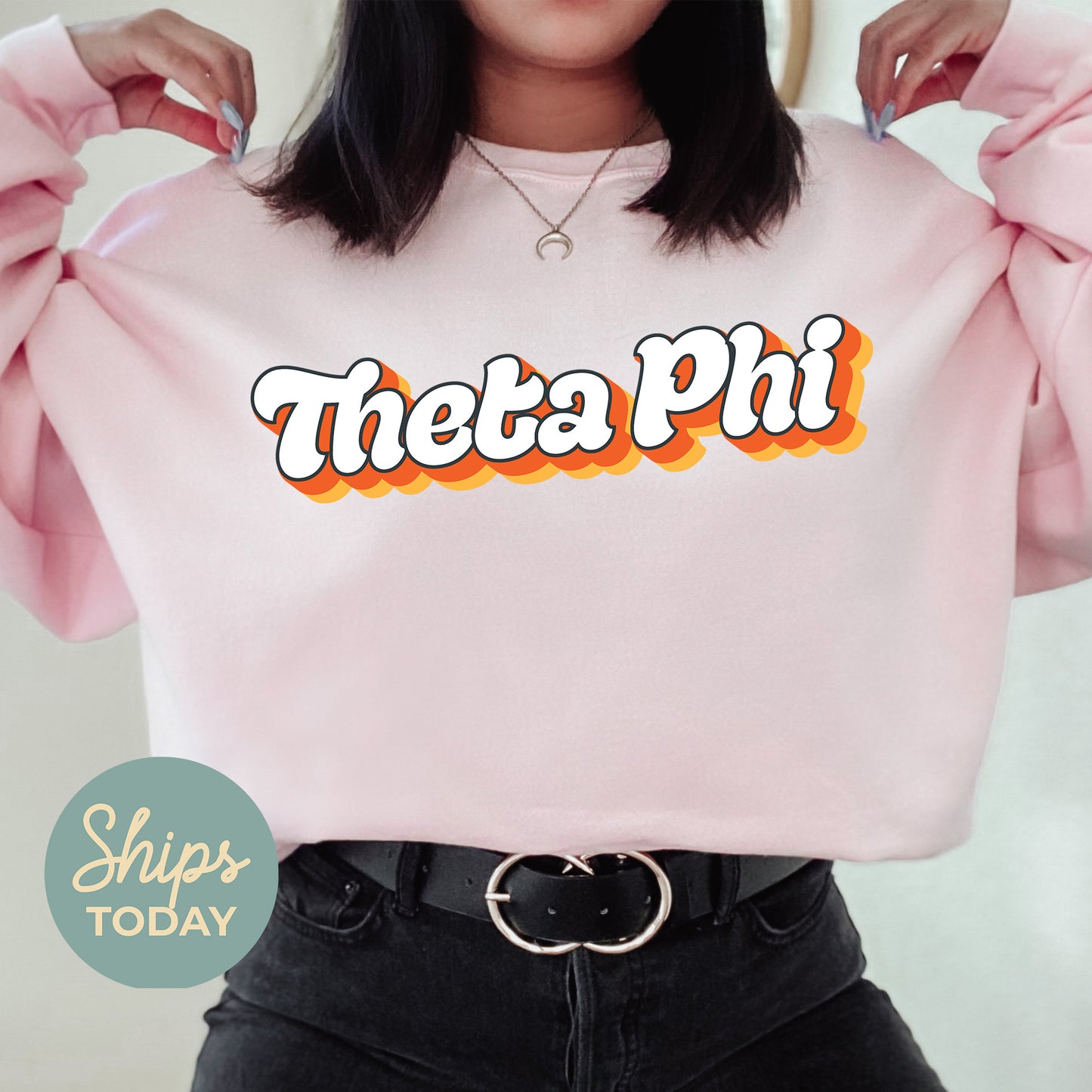 a woman wearing a pink sweatshirt with the word thea phi on it