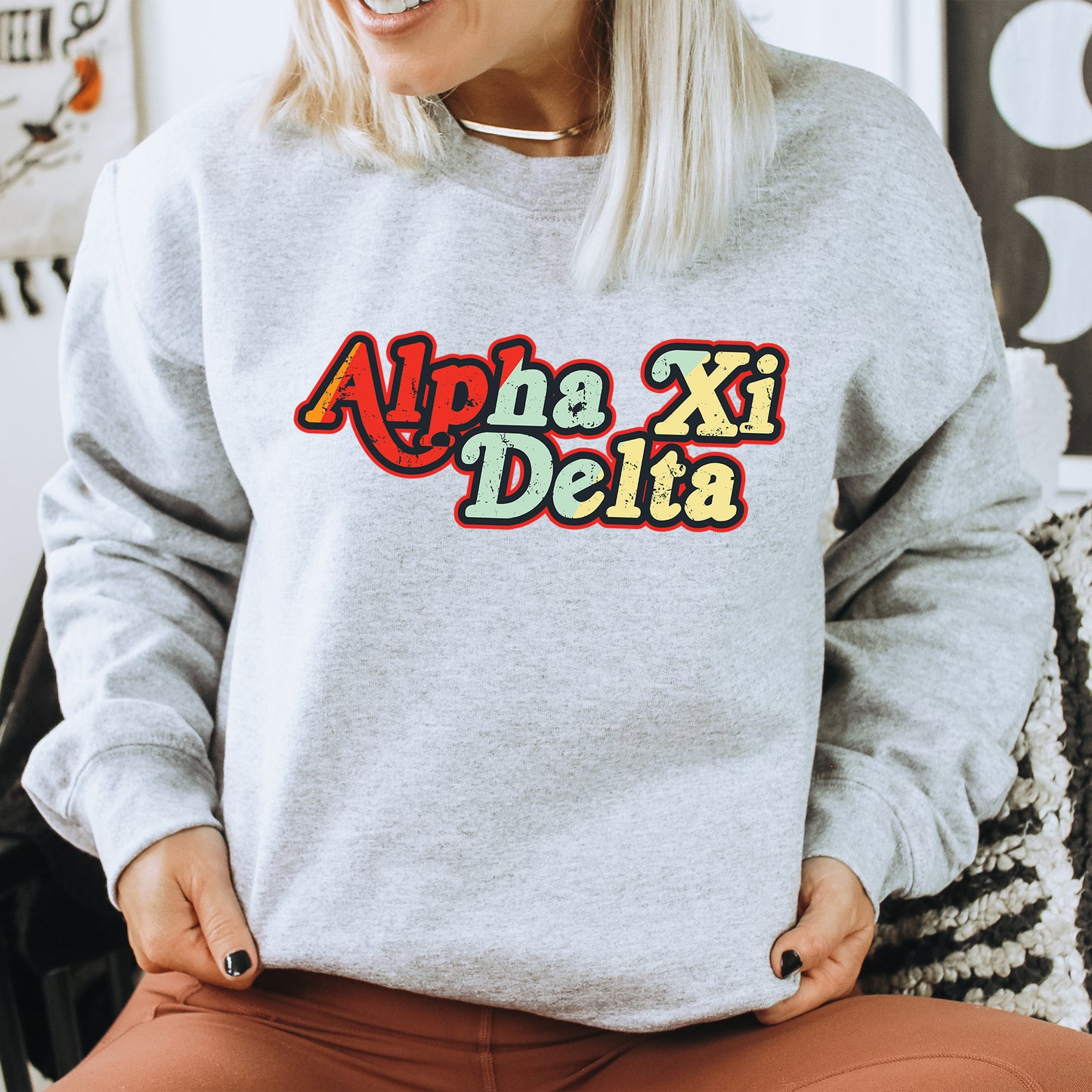 a woman sitting on a chair wearing a sweatshirt that says apha xi delta